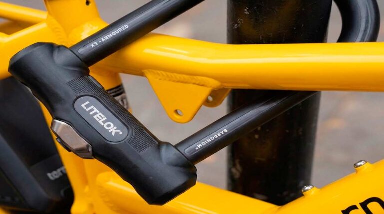 Bright yellow Tern GSD electric cargo bike with blue child seats parked on a city sidewalk